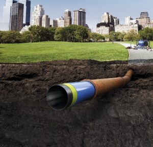 Sistema Primus Line para rehabilitación sin zanja de tuberías de acero al carbono en entorno urbano en Colombia, mostrando inserción de liner flexible de alta presión dentro de tubería existente en sección de suelo